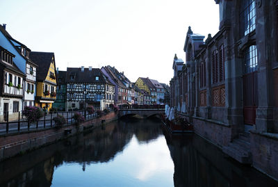 Canal amidst buildings against sky in city