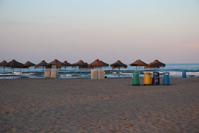 Built structure on beach by sea against sky during sunset