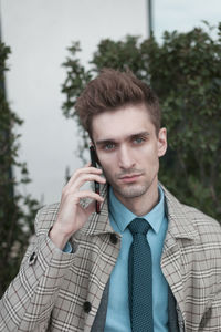 Portrait of businessman talking on mobile phone in city