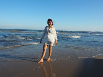 Full length of woman standing on beach against clear sky