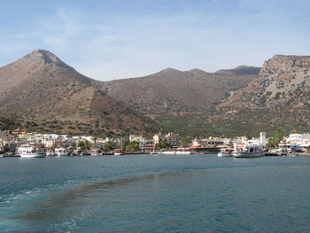 Boats moored at harbor against mountains