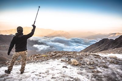 Man standing on snowcapped mountain against sky