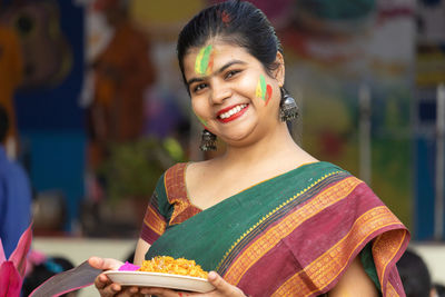 An indian woman with colorful face looking at camera in holi - the festival of colors