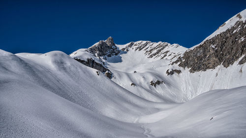 Scenic view of snowcapped mountains against clear blue sky