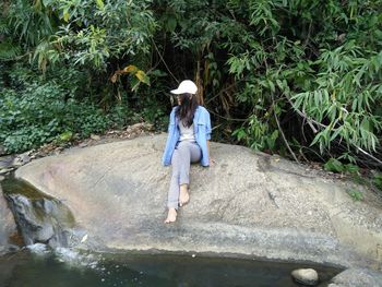 Full length of woman standing on rock against plants