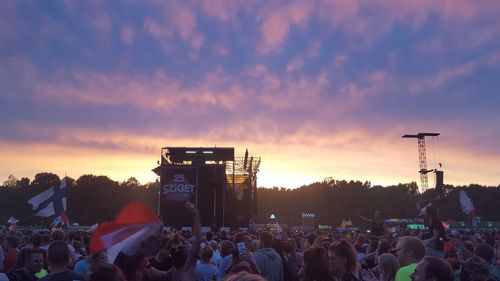 People at music concert against sky during sunset