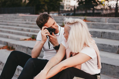 Young woman photographing while sitting on camera