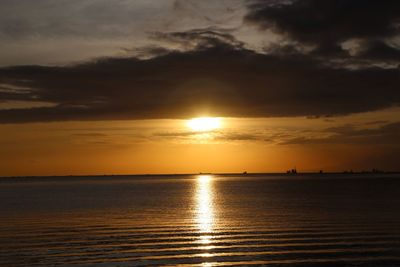 Scenic view of sea against dramatic sky during sunset