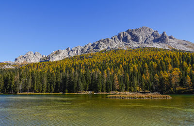 Scenic view of lake and mountains against clear blue sky