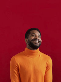 Young man standing against yellow background