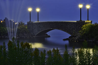 Arch bridge over river against sky at night