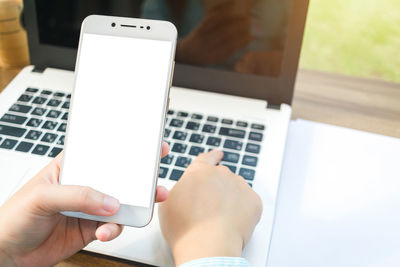 Close-up of businesswoman using laptop and mobile phone on table