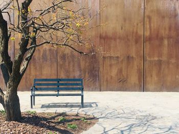 Empty bench in park against wall