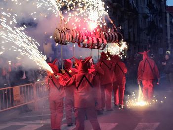 Rear view of people wearing costumes with firework display at night