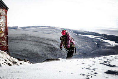 Rear view of person walking on snow covered landscape