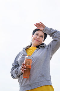 Portrait of young woman standing against sky over white background