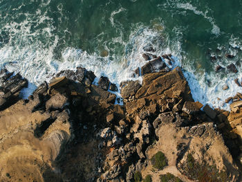 Aerial view of sea waves splashing on rocks