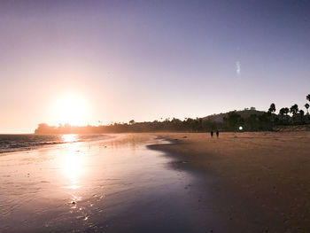 Scenic view of beach against clear sky during sunset