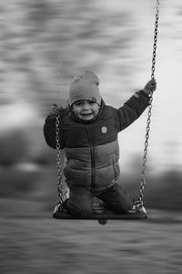 Portrait of boy standing on swing at playground