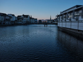 Bridge over river by buildings against sky in city