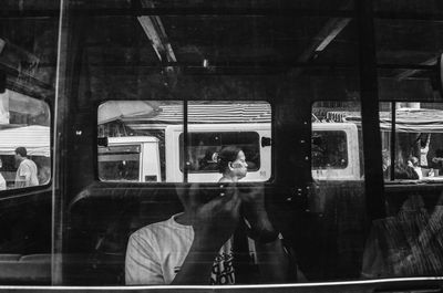 Reflection of woman photographing in bus