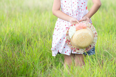 Midsection of woman holding pink flower on field