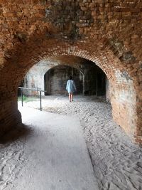 Rear view of woman walking in archway