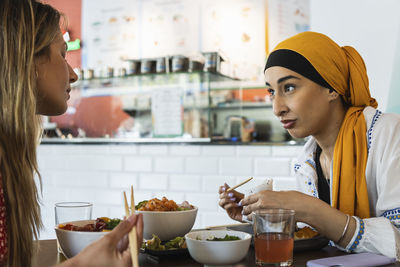 Young women talking with each other while having food in restaurant