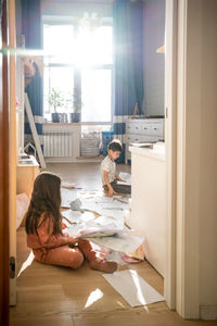 Rear view of woman sitting on floor at home