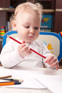 Cute girl holding pencil on table