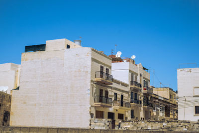 Low angle view of buildings against clear blue sky