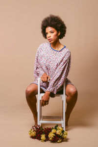 Portrait of young woman sitting against wall