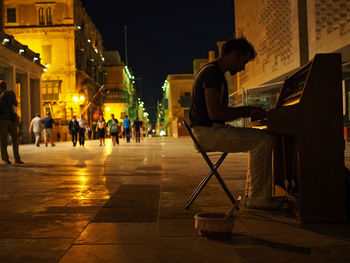 Side view of street musician playing piano in city