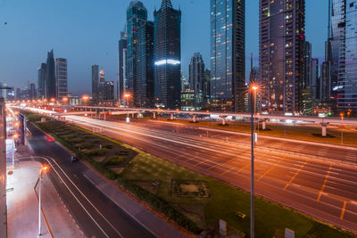 Light trails on road amidst buildings in city at night