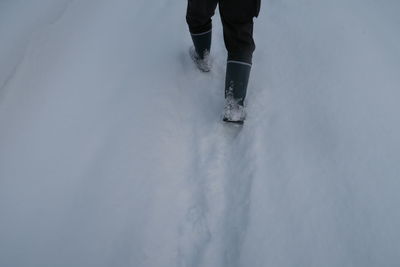 Low section of person walking on snow covered land