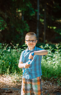 Portrait of boy with soap bubbles  standing in forest