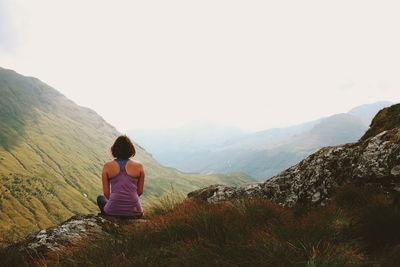 Rear view of woman looking at mountains against sky
