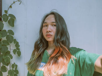 Portrait of young woman standing against wall