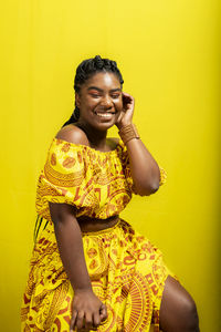 Young woman wearing colorful long clothes over yellow background. natural expression.