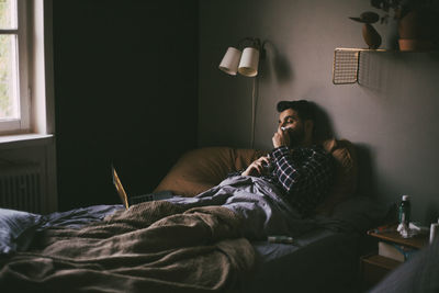 Sick man blowing nose while having online consultation on laptop at home