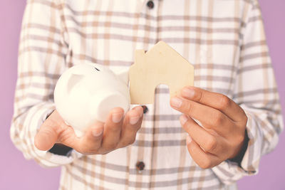 Midsection of boy holding piggy bank and toy house