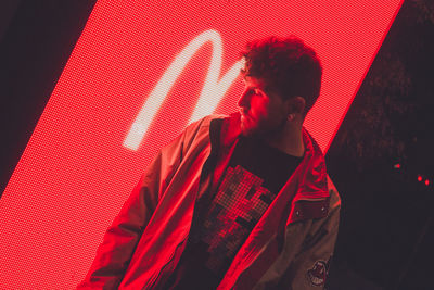 Midsection of man standing against illuminated wall at night