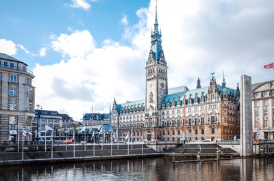 Hamburg town hall by river against sky