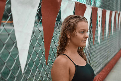 Portrait of woman standing by chainlink fence