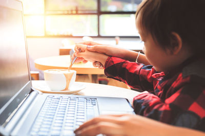Midsection of man using mobile phone while sitting on table