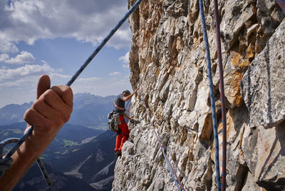 Close-up of hand holding clothes hanging against sky