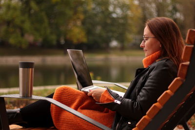 Beautiful redhead young woman sitting in the park and using laptop. student. university. freelance.