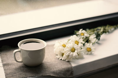 High angle view of coffee and white roses on table