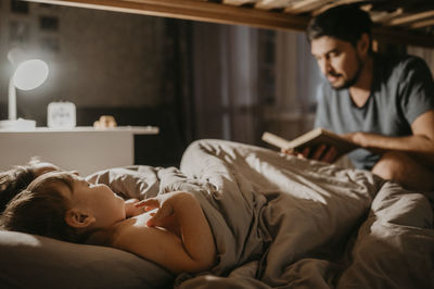 Father reading book to children on bed