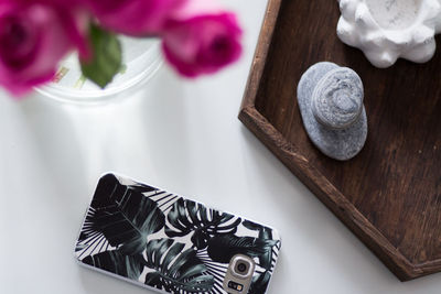 High angle view of flower vase and phone on table